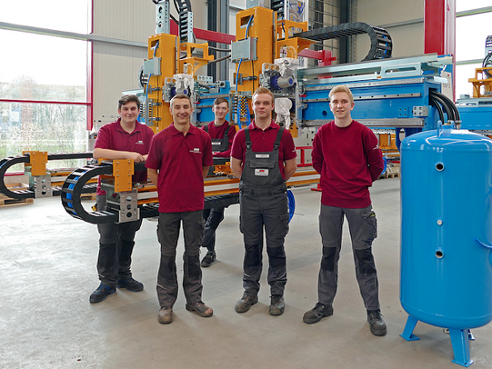 Five apprentices in work clothes are standing in a workshop at Horstkemper Maschinenbau 