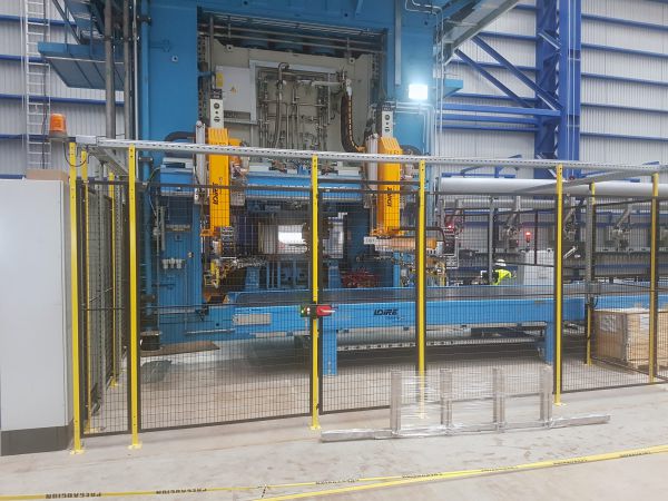 Frontansicht einer Presshärteanlage mit angeschlossenem Auslaufband. Die gefertigten Bauteile werden nach dem Pressprozess automatisch aus der Anlage ausgeschleust.