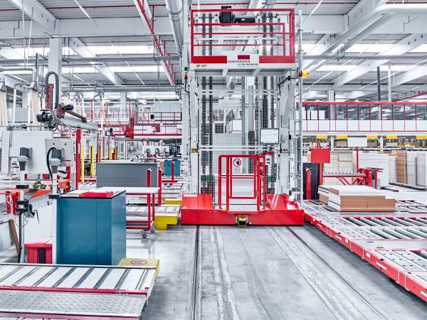 Gesamtansicht eines Transferwagens auf Schienen in einer automatisierten Fertigungslinie. Der Wagen übernimmt den Transport von Materialstapeln zwischen den einzelnen Produktionsstationen.