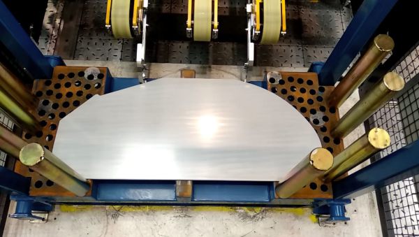 Halbkreisförmiges Metallteil in einer blauen Ausrichtstation mit mehreren goldfarbenen Führungsstiften