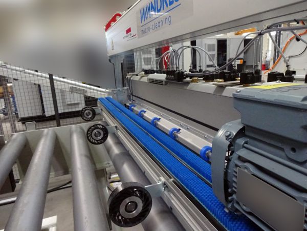 Detailansicht einer Bürstenreinigungs- und Beölungsanlage mit Rollenförderer und Transportband zur Oberflächenbehandlung von Platinen.