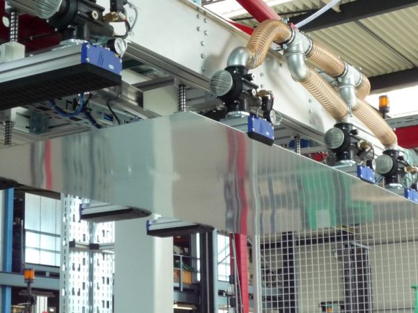 Industrielle Sauganlage mit mehreren Saugsystemen und flexiblen Schläuchen in einer Produktionshalle