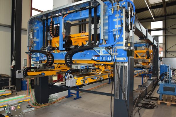 Große blaue und gelbe Transfersystemanlage mit mehreren Schienen, Kabelketten und pneumatischen Komponenten in einer Industriehalle