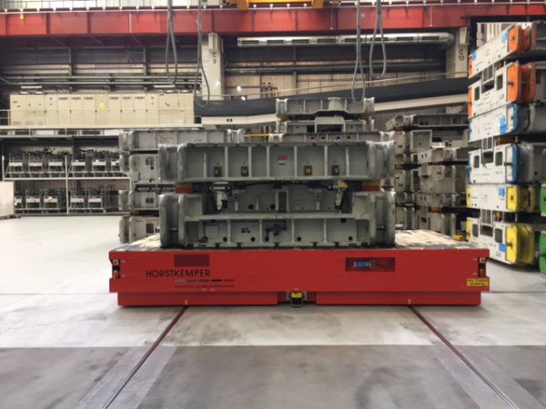 Roter Werkzeugfahrwagen mit grauer Metallkonstruktion in einer großen Industriehalle