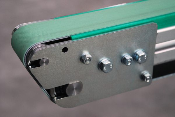 Nahaufnahme eines grünen Riemenförderers mit Metallrahmen und Schraubenbefestigung