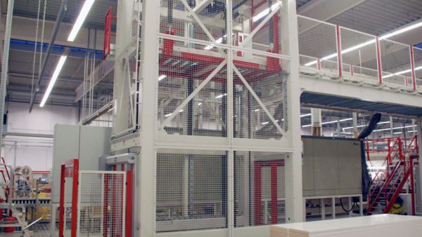 Lifting station with conveyor belt and safety guardrail in an industrial building 