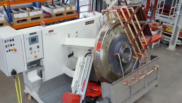 An angled view of a crack test bench with a large roller bearing ring clamped in place. The workpiece is in the test position within the clamping and rotating device.