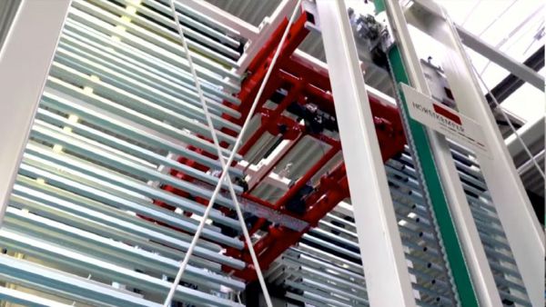 Close-up view of the lifting and transport unit of a sorting buffer unit. The red transport unit has moved between the storage bins and is positioned at the level of a storage location. 