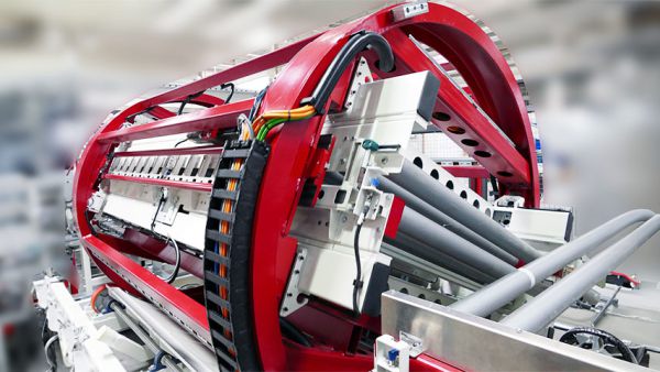 Roter Trommelwender mit grauen Walzen und Kabeln in einer Industriehalle