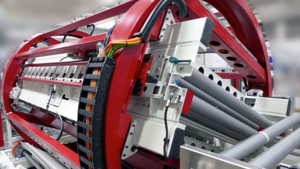 Roter Trommelwender mit grauen Walzen und Kabeln in einer Industriehalle