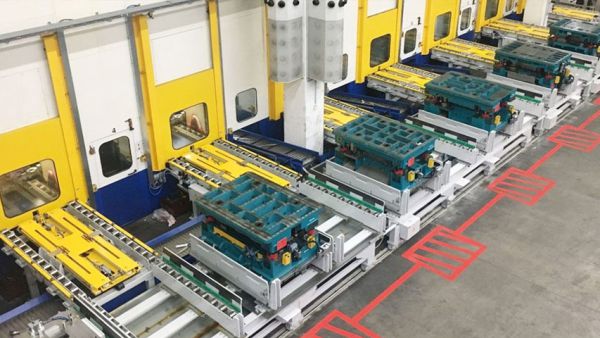 Blick auf eine Werkzeugwechselanlage mit mehreren Werkzeugwagen vor einer Reihe von Pressenstationen.