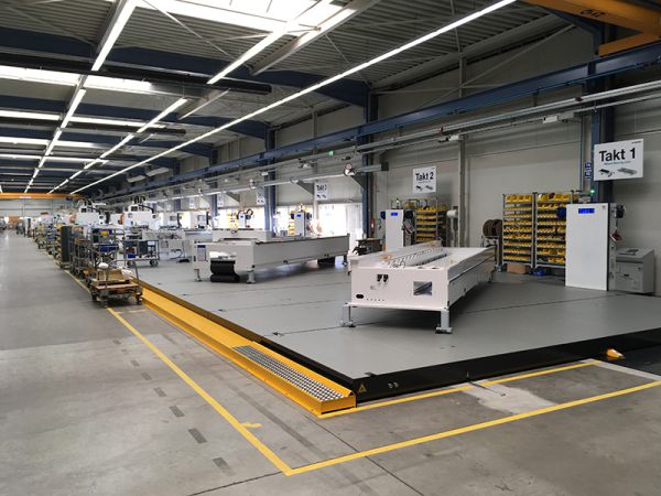 Fließmontagelinie mit mehreren Montagestationen und zentralem Taktantrieb in einer großen Industriehalle