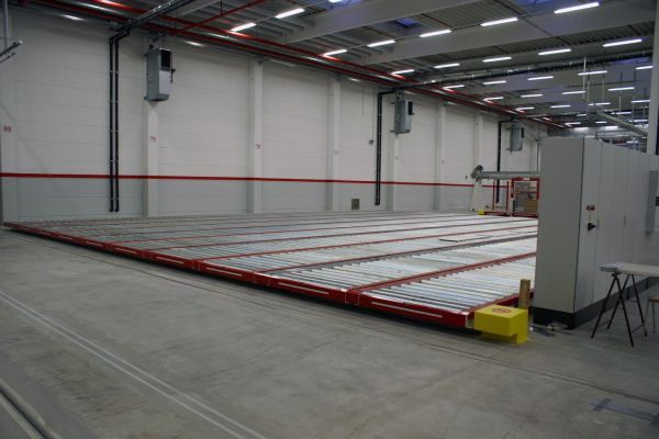 Rollenförderer in einer Lagerhalle mit langen Rollenbahnen und modernen Industrie-Wänden.