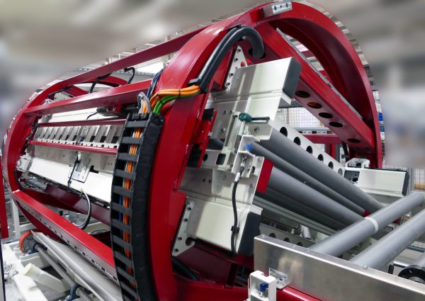 Roter Trommelwender mit grauen Walzen und Kabeln in einer Industriehalle