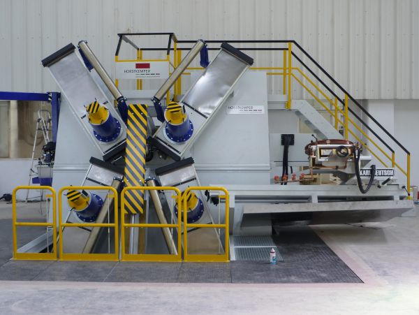Rissprüfstand mit vier Magnetpulvergeräten, Warnmarkierungen sowie gelben Schutzgeländern und Treppe.