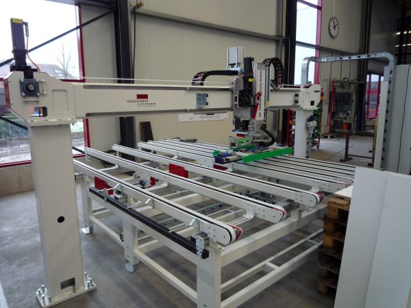 Portal-Feedersystem mit mehreren Förderbändern und einem beweglichen Greifarm in einer Industriehalle