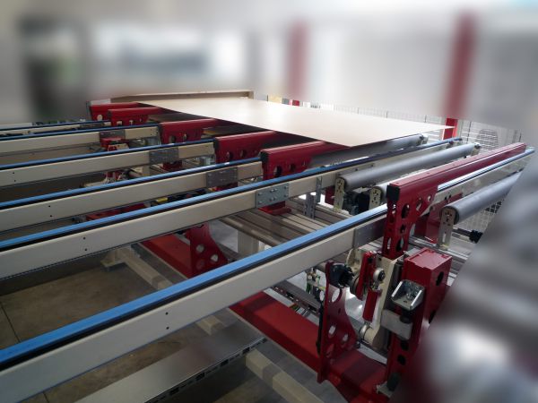 Hubrechen in einer Beschickungsanlage, die im 90°-Winkel zueinander angeordnet sind, mit roten und silbernen Metallteilen und Förderstrecken für Produkte.