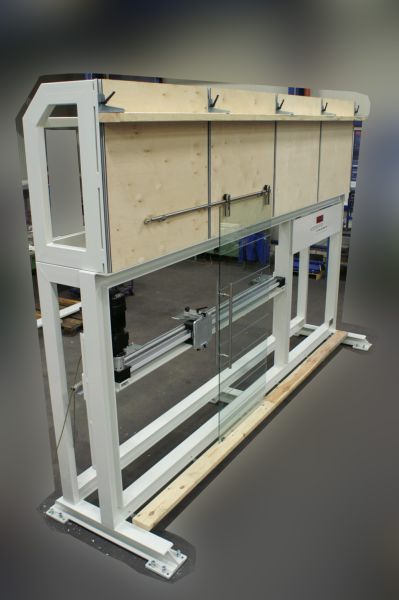 Belastungsprüfstand mit eingespanntem rechteckigem Glasscheiben-Probenrahmen aus Aluminiumprofilen und Holzverkleidung im Hintergrund