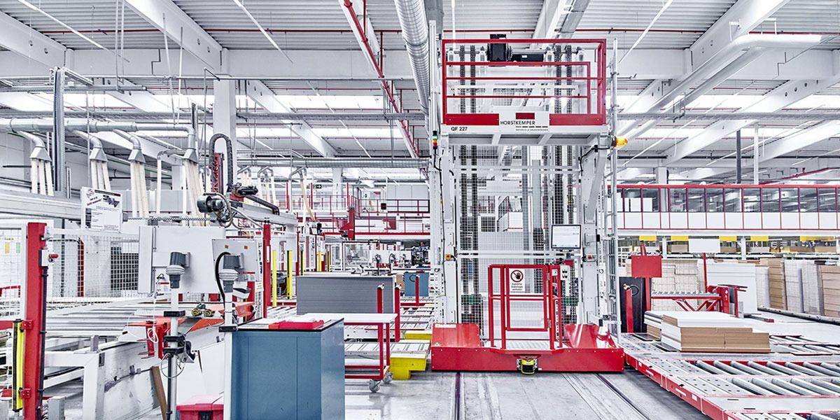 Overall view of a transfer vehicle on rails in an automated production line. The vehicle transports stacks of material between the individual production stations.