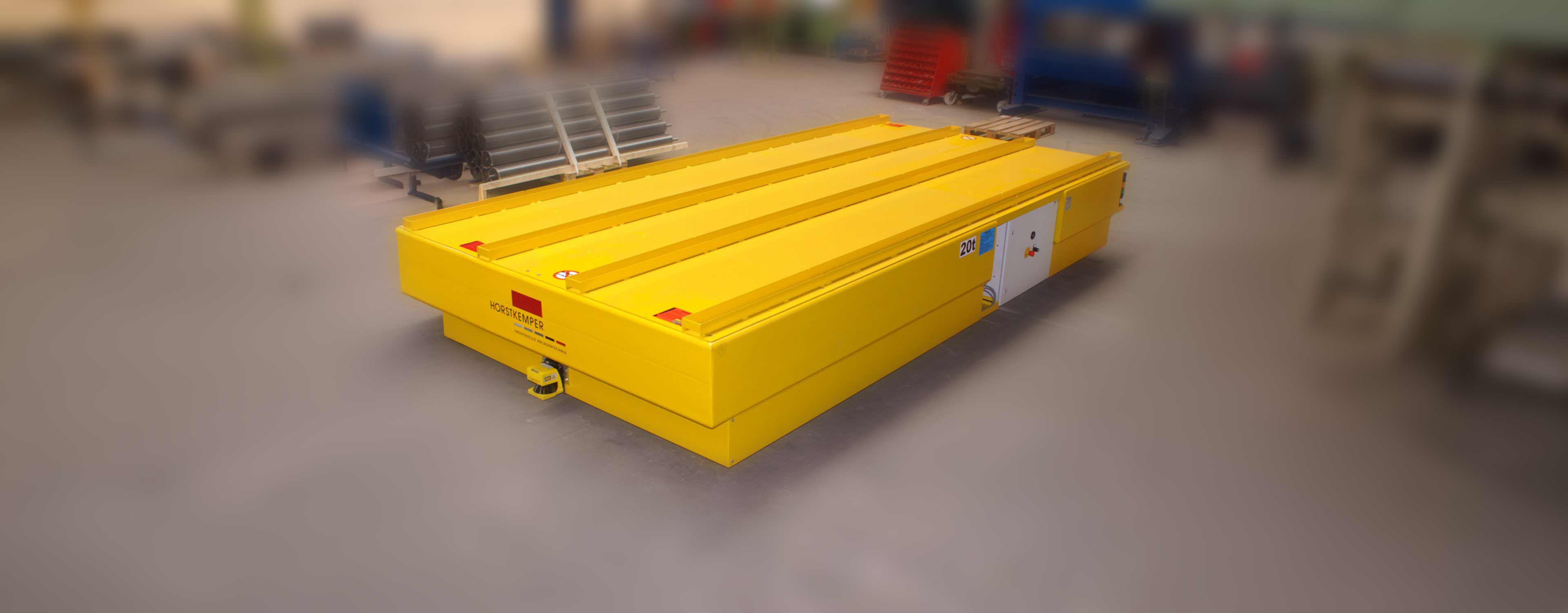 Yellow industrial vehicle with a flat surface, ideal for transporting heavy loads in workshops.