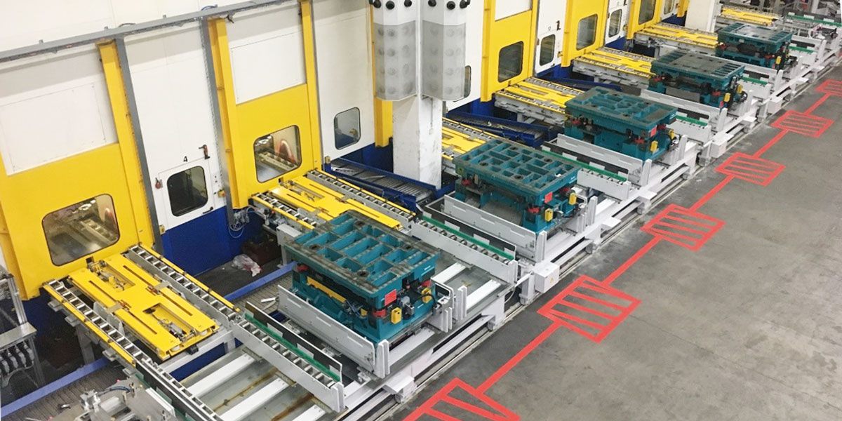 Blick auf eine Werkzeugwechselanlage mit mehreren Werkzeugwagen vor einer Reihe von Pressenstationen.